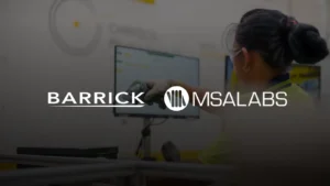 Laboratory technician scanning a sample jar at a PhotonAssay™ unit, with Barrick and MSALabs logos overlaid