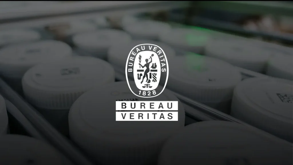 Ore sample jars on a PhotonAssay™ conveyor system with Bureau Veritas logo overlaid