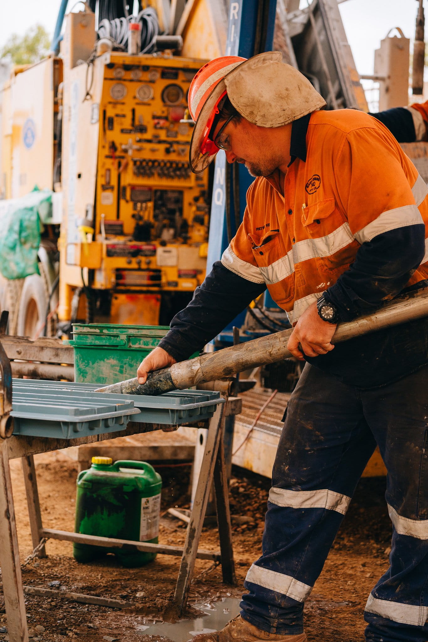 Geologist in orange hi-vis handling a drill core sample at a rig site at Ravenswood Gold Mine, Queensland