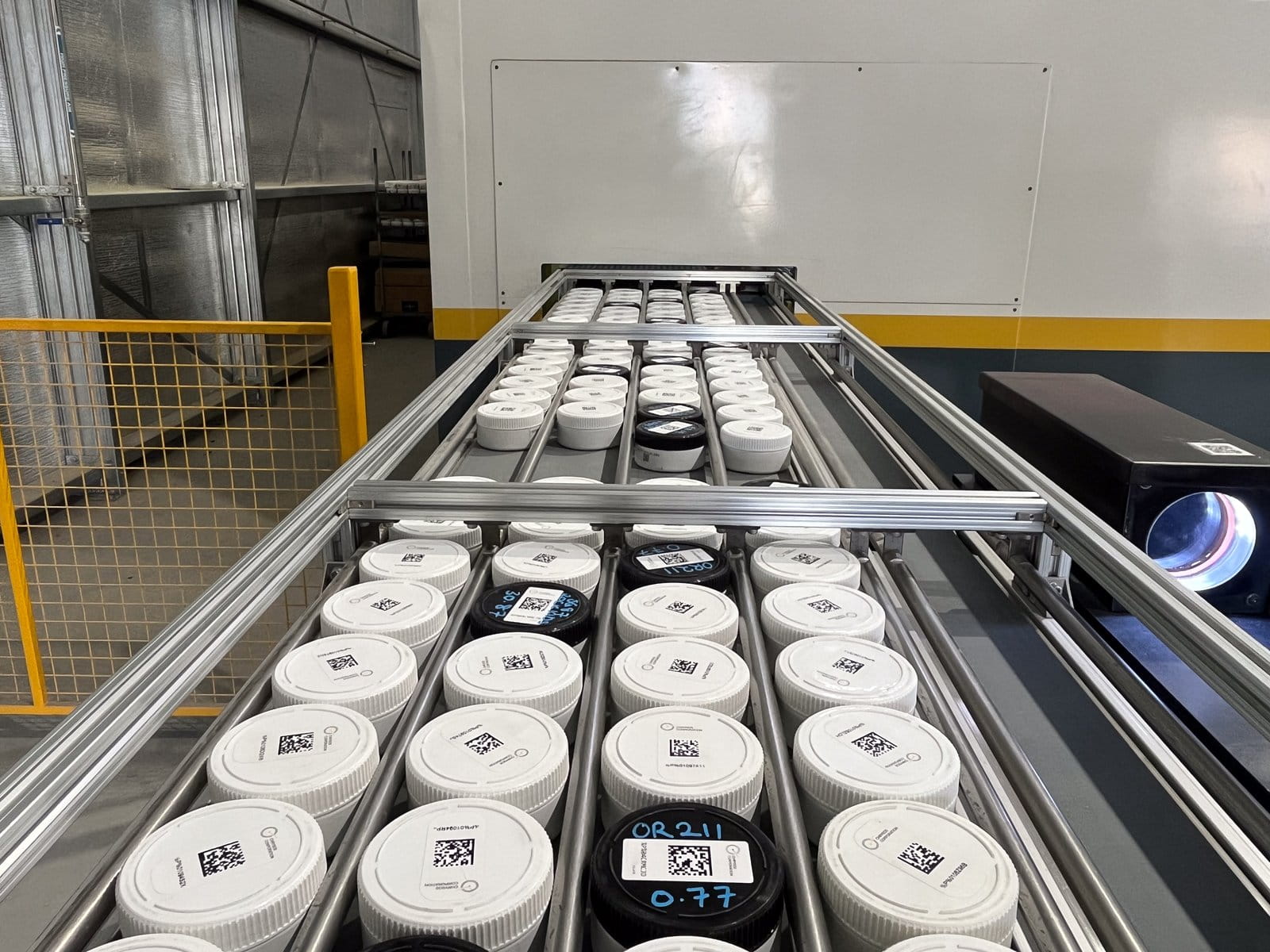 Close-up of barcoded PhotonAssay™ sample jars loaded onto the automated conveyor tray at Ravenswood Gold Mine, Queensland