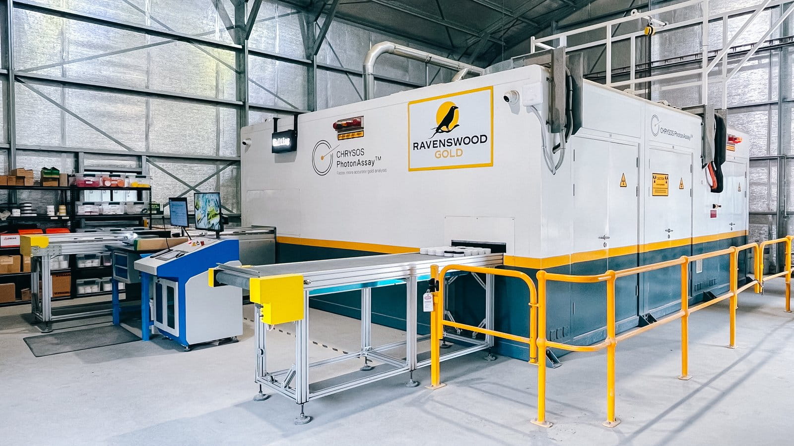 Chrysos PhotonAssay™ 1408X unit installed inside the Ravenswood Gold Mine facility, Queensland, showing the full cabinet with Ravenswood Gold branding and yellow safety barriers