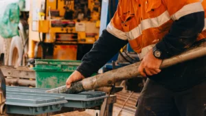 Geologist in orange hi-vis handling a drill core sample at a rig site, placing it into a sample tray as part of PhotonAssay™ process