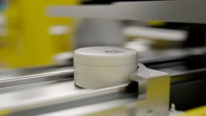 A cylindrical ore sample jar moving along the automated conveyor rail inside a PhotonAssay™ unit