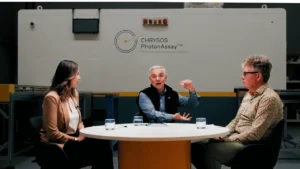 Dr Naomi Potter, Dr Simon Dominy, and Dr James Tickner in discussion in front of PhotonAssay™ unit at Chrysos Corporation headquarters