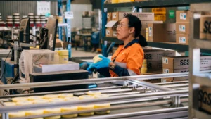 SGS Kalgoorlie laboratory technician in PPE inspecting a PhotonAssay sample jar at a workstation